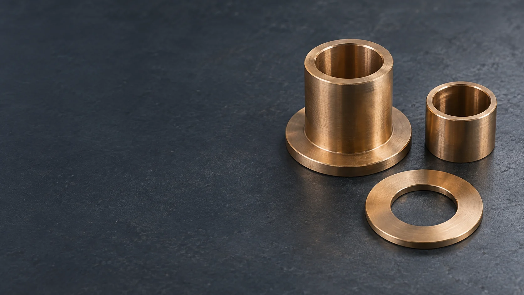 Bronze flanged bushing, plain sleeve and thrust washer on a dark work surface