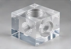 Clear block with machined bores — AI illustration, not a vetcnc photograph or a verified PMMA sample